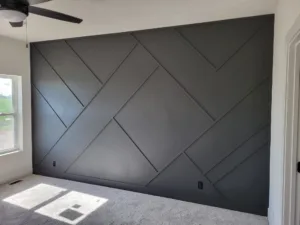Geometric diagonal pattern accent wall painted dark gray, fully finished with two windows and a ceiling fan