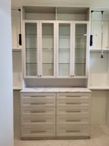 Painted built-in cabinet with glass front doors, marble countertop, and multi drawer base storage