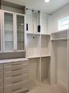 Finished closet cabinetry with glass front doors, marble style countertop, and open shelving with rod