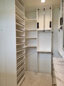 Closet corner shelving with vertical dividers, diagonal shoe shelving, and a hanging rod, finished white