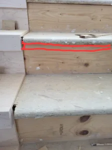 Built-up wood stair tread block at a stair nose, raw framing stage before trim installation