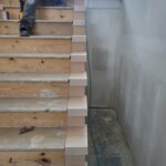 Finished risers installed on staircase—light wood vertical boards between treads, raw wood stage before paint.