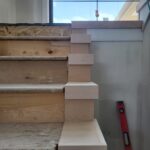 Interior stair end caps (false treads) installed at wall junction, raw wood ready for paint or stain.