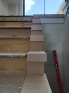 Unfinished wood stair risers and treads installed on stringers, no railing or balusters visible