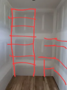 Closet walls marked with red layout lines showing planned shelf and rod placement before installation.