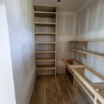 Multiple custom closet shelves under construction with raw wood framing and installed shelving units.