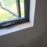 Interior window sill installed at base of exterior window opening, raw wood finish ready for paint.
