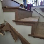 Stair skirt board and handrail installed in raw wood finish, ready for paint.