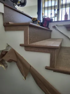 Curved oak stair treads with white risers and handrail installed, protective paper still on treads