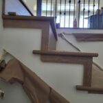 Horizontal rod railing with blue knots installed on interior staircase alongside finished wood handrail and nosing.