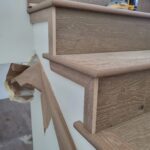 Finished wood skirt board and stair treads installed, raw wood stain applied, ready for final sanding and paint.