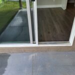 Installed exterior sliding glass patio door with white frame, threshold, and interior casing trim.