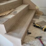 Finished wood stair risers and treads installed with skirt board, raw wood ready for paint.