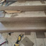 Finished wood stair treads and risers installed, raw wood ready for paint, with construction materials on site.