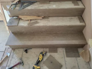 Oak stair treads and risers installed on stairway, tools staged on steps, unfinished