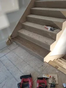 Long run of oak stair treads and risers installed with skirt board, subfloor construction visible
