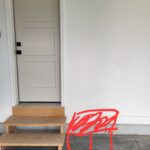 Finished interior door with white painted three-panel slab, lockset, and casing installed in opening with baseboard.