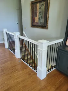 Landing with white painted newel posts and vertical black iron balusters below