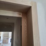 Door jamb extension strips installed on interior side of doorway, raw wood ready for paint.