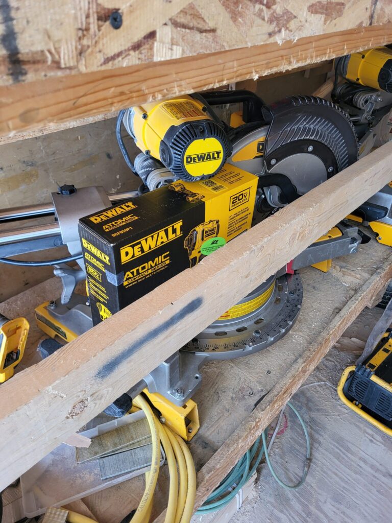 DeWalt miter saw and stand stored with jobsite tools.