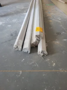 Staged trim material bundled on a concrete floor, tagged and awaiting installation