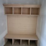 Custom built-in mudroom locker with four open cubbies on lower tier, solid middle shelf, and four upper cubbies—raw wood, ready for paint.