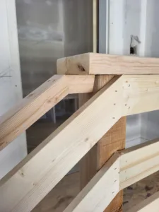 Raw wood framing joinery at a post and rail connection, rough carpentry stage