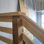 Close-up of a wooden handrail joint showing craftsmanship and joinery details during the installation process.