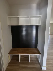 Built-in bench nook with white face-frame cubbies above and dark shiplap backing, wood bench seat below.