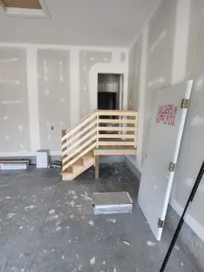 Small unfinished wood staircase and horizontal slat railing framed inside a room during construction.