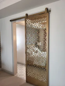 Bronze scrollwork barn door hung on an overhead track, hardware fully installed