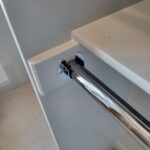 Close-up of a towel bar installation showing the mounting hardware and finish details in a bathroom setting.