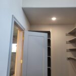 Painted interior door with casing and lockset installed in finished room with built-in shelves.