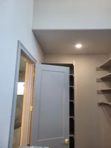 Painted door with casing and lockset installed in a finished room, shelving visible at the edge