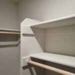 Closet shelving with painted white shelves, wood hanging rod, and finished trim.