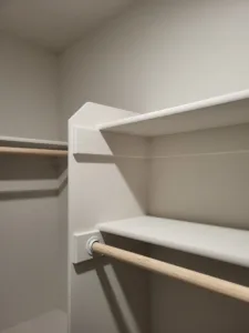 Closet shelf corner detail with a painted white shelf and wood hanging rod, finished trim