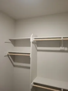 Closet shelving with a shelf and two hanging rods below, painted white finish installed