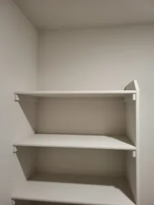 Built-in corner shelving with two painted white shelves and visible support brackets