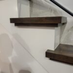 This photo shows a finished wood wall cap installed on a staircase, highlighting the clean lines and craftsmanship of the trim work.
