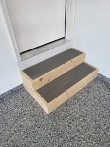 Two closed riser garage steps with dark stained treads and natural wood sides, flake floor below