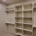 Finished face-frame closet shelving with multiple tiers, hanging rods, and painted white trim.