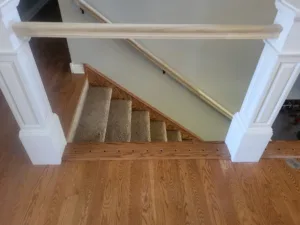 Wood trim at the stair opening with a plugged nail pattern, finished newel posts nearby