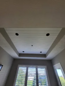 Painted white shiplap tray ceiling with recessed lighting above a bay window nook