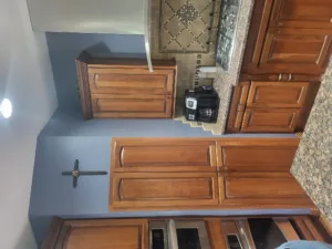 Stained wood kitchen cabinets installed with hardware, granite countertop, and tile backsplash