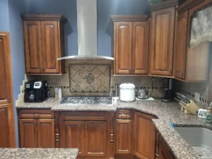 Finished kitchen with stained wood cabinetry, granite countertops, and decorative backsplash tile