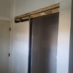 This photo shows the installation stage of a pocket door system, highlighting the track and framing before the door is hung.