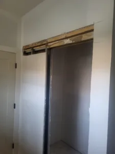 Barn door opening with wood backer board and overhead track installed, no door slab hung yet