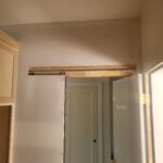 Barn door frame with overhead track and 1x8 backer board installed, ready for door slab and hardware.