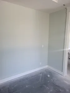 White painted baseboard trim installed along the wall perimeter over a bare subfloor