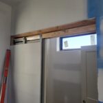 Barn door track and header frame installed above window opening, ready for door slab and hardware.